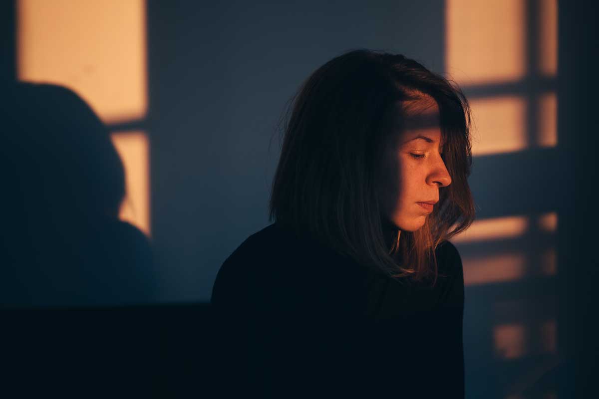 A woman sitting alone and depressed in window light